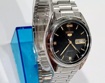 Reloj vintage para hombre Seiko Automático 7009, esfera negra y marcadores dorados.