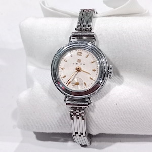 May include: A vintage Seiko wristwatch with a round silver-tone case and a matching metallic link bracelet. The off-white dial features gold-tone hour markers, a gold-tone hand set, and a small sub-dial for seconds at the six o'clock position.