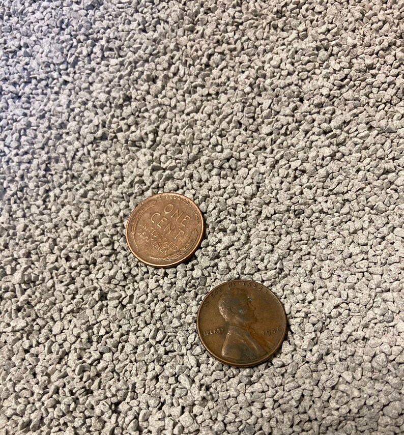 May include: Two copper pennies on a gray, textured surface. One penny shows the words "ONE CENT" and "UNITED STATES OF AMERICA". The other penny has a profile of a person and the year 1928.