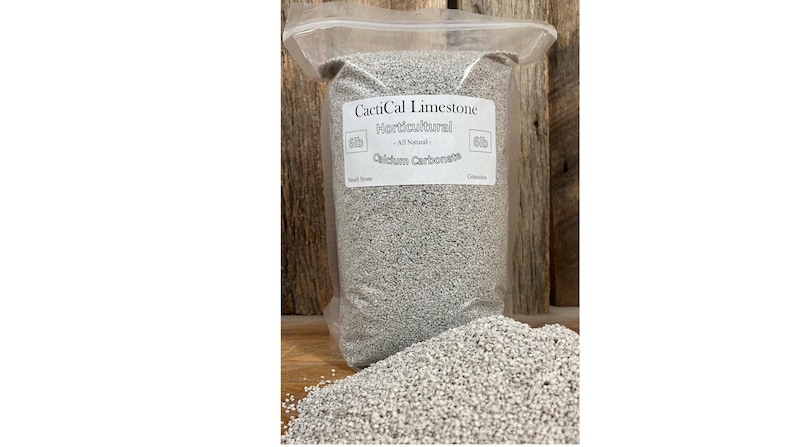 May include: A clear plastic bag filled with horticultural limestone. The bag has a white label with the text "CactiCal Limestone Horticultural - All Natural - Calcium Carbonate". A pile of the limestone is in front of the bag.