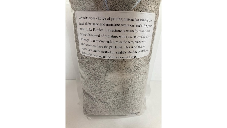 May include: A clear plastic bag filled with light gray potting mix. A white label with black text provides instructions for use, including drainage and moisture retention for plants. The mix contains pumice and limestone.