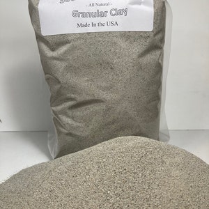 May include: A clear plastic bag filled with granular clay, labeled "Seven Springs Farm Sodium Bentonite." The label also states "All Natural," "Granular Clay," and "Made In the USA." A pile of the granular clay is in front of the bag.