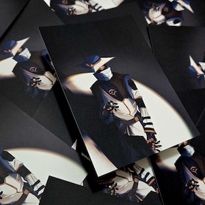 May include: A collection of black art prints featuring a character in a blue and white outfit with a mask and hat. The character is illuminated by a spotlight, with a dark background.