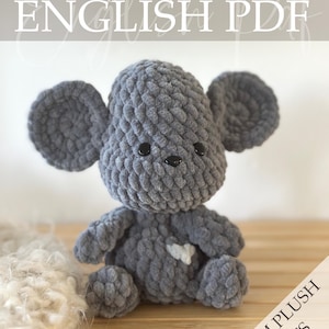 Op de afbeelding: Een grijze gehaakte muis knuffel met grote oren, zwarte knoopogen en een witte hartvormige patch. De tekst "Crochet Pattern ENGLISH PDF" staat bovenaan en "PALM PLUSH PETS" rechtsonder.