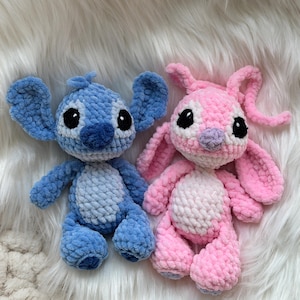 May include: Two handmade crochet plush toys featuring large ears and round black eyes. One toy is light and dark blue with a lighter blue belly patch, while the other is light and dark pink with a lighter pink belly patch and long antennae.