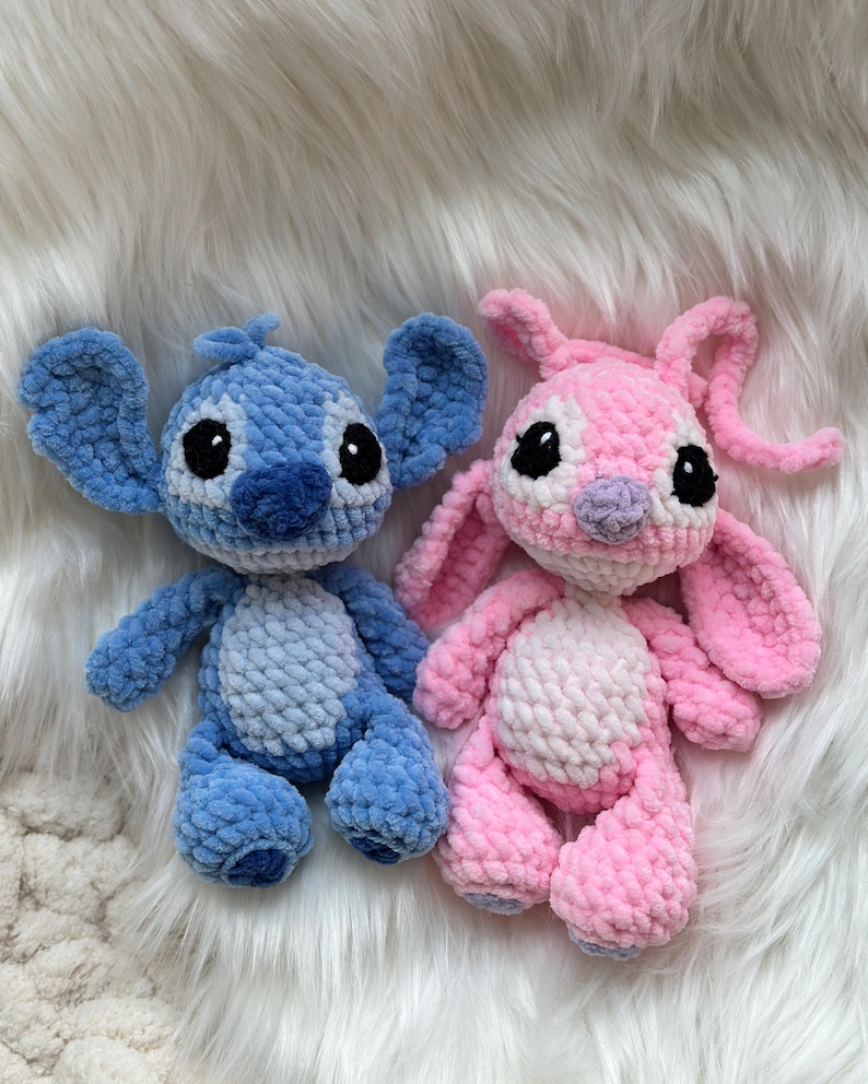 May include: Two handmade crochet plush toys featuring large ears and round black eyes. One toy is light and dark blue with a lighter blue belly patch, while the other is light and dark pink with a lighter pink belly patch and long antennae.