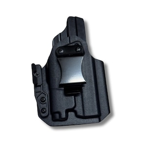 May include: Black polymer holster with a silver-colored metal belt clip. The holster has a molded design with visible screw heads and a textured surface. The clip is secured with two screws.