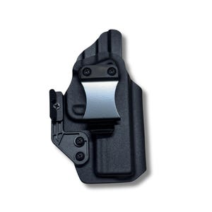 Op de afbeelding: Zwarte polymeer holster met een metalen riemclip. De holster heeft een gegoten ontwerp met zichtbare schroefkoppen. De clip is zilverkleurig en de holster is ontworpen om in de tailleband te worden gedragen.