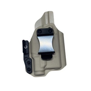 A tan-colored holster with a black metal clip attached to it.