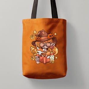 May include: Orange tote bag with a cartoon illustration of a witch reading a book with a fox. The witch wears a brown hat with pumpkins and glasses. The design includes autumn leaves and stars, ideal for Halloween or autumn.