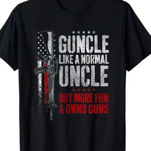 May include: Black t-shirt with a graphic design featuring a stylized rifle and the text "GUNCLE LIKE A NORMAL UNCLE BUT MORE FUN & OWNS GUNS" in white and red. The design incorporates an American flag motif.