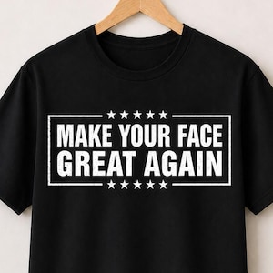 May include: A black short-sleeved t-shirt featuring a white rectangular border with the text "MAKE YOUR FACE GREAT AGAIN" printed in the center, flanked by five white stars above and five white stars below the text, all displayed on a hanger.