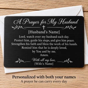 May include: A rectangular black metal wallet card featuring white engraved text that reads A Prayer for My Husband, followed by a prayer, placeholders for names, and the closing With all my love, all accented with decorative leaf motifs.