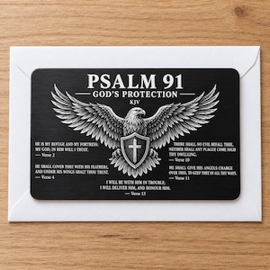 May include: A rectangular black metal card featuring a white graphic of an eagle with wings spread wide, holding a shield with a cross. The text reads PSALM 91 GOD'S PROTECTION KJV, followed by verses 2, 4, 10, 11, and 15 in white lettering.