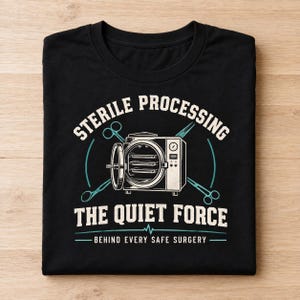 May include: A black t-shirt featuring a graphic of an autoclave with surgical scissors crossed behind it. The text reads: STERILE PROCESSING THE QUIET FORCE BEHIND EVERY SAFE SURGERY. The design uses cream and teal colors on the black fabric.