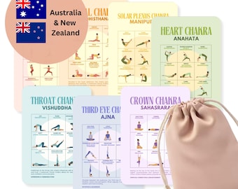 May include: A set of seven rectangular yoga pose cards, each color-coded to represent a specific chakra, featuring illustrations of yoga postures and text labels. A light pink drawstring storage pouch is positioned in the foreground.