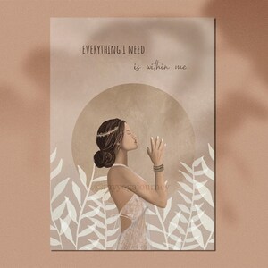 May include: An art print featuring a woman in a white dress with her hands clasped in prayer. The print has the text "EVERYTHING I NEED is within me" and is set against a beige background with floral accents. The artwork has a spiritual theme.