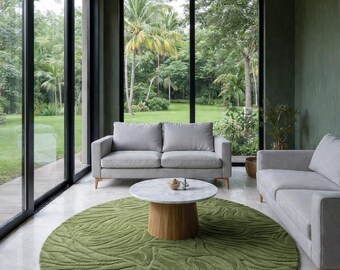 May include: A modern living room with a gray sofa, a round marble-topped coffee table, and a green patterned rug. The room has large windows overlooking a lush green yard. The walls are painted in a muted green color.