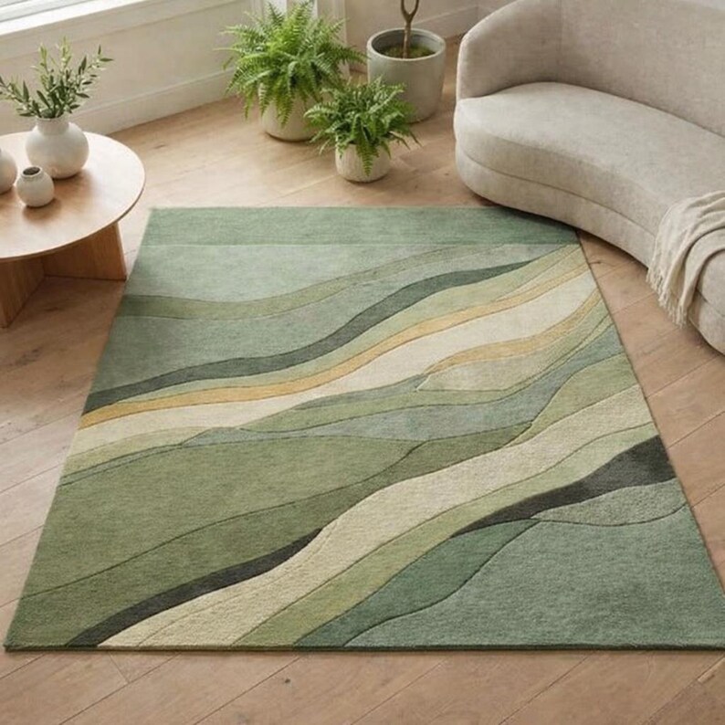 Pu&ograve; includere: Un tappeto rettangolare con un design astratto nei toni del verde, beige e giallo. Il tappeto presenta un motivo a onde, creando un senso di movimento. Il tappeto &egrave; posato su un pavimento in legno ed &egrave; circondato da piante e mobili.