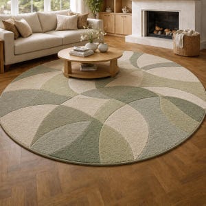 May include: A large, round area rug with a geometric design in shades of green and beige. The rug is placed on a hardwood floor and features a curved pattern. The rug is a decorative element in a living room setting.