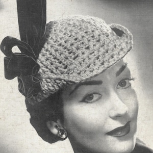 May include: A crocheted bowler hat with a black velvet ribbon. The hat is worn by a woman with dark hair and a light complexion.
