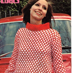 Puede incluir: Un suéter de lunares rojos y blancos con cuello alto. El suéter lo lleva puesto una mujer de pie junto a un coche rojo. El texto "BritKnits Vintage" es visible en la parte inferior de la imagen.