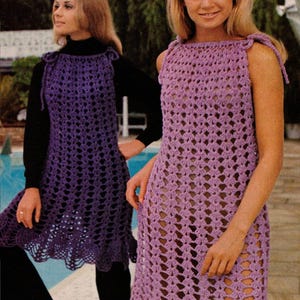 May include: Two women modelling vintage crochet dresses. One dress is a deep purple, the other a lighter lavender. Both dresses are sleeveless with a scalloped hem. The dresses are worn with black clothing. The image has the text "BritKnits Vintage".
