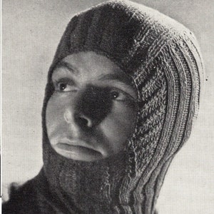 May include: A black and white photo of a person wearing a knitted balaclava. The balaclava is a 3-ply design with a ribbed texture.