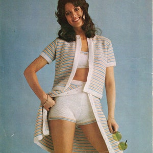 Puede incluir: Un conjunto de top y pantalones cortos de punto a rayas en azul, blanco y naranja. El top tiene manga corta y cierre de botones en la parte delantera. Los pantalones cortos son de cintura alta y tienen pierna ancha.