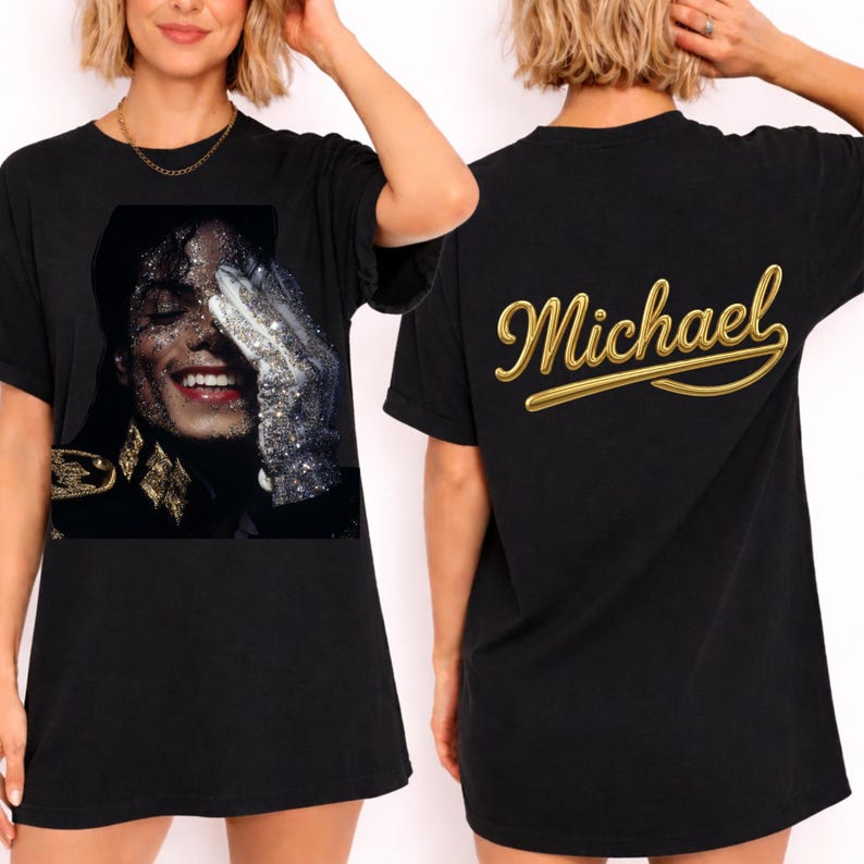 May include: Black t-shirt featuring a glittery image of Michael Jackson on the front. The image shows Jackson wearing a glove and smiling. The back of the shirt has the name "Michael" in gold script. A classic tee for music fans.