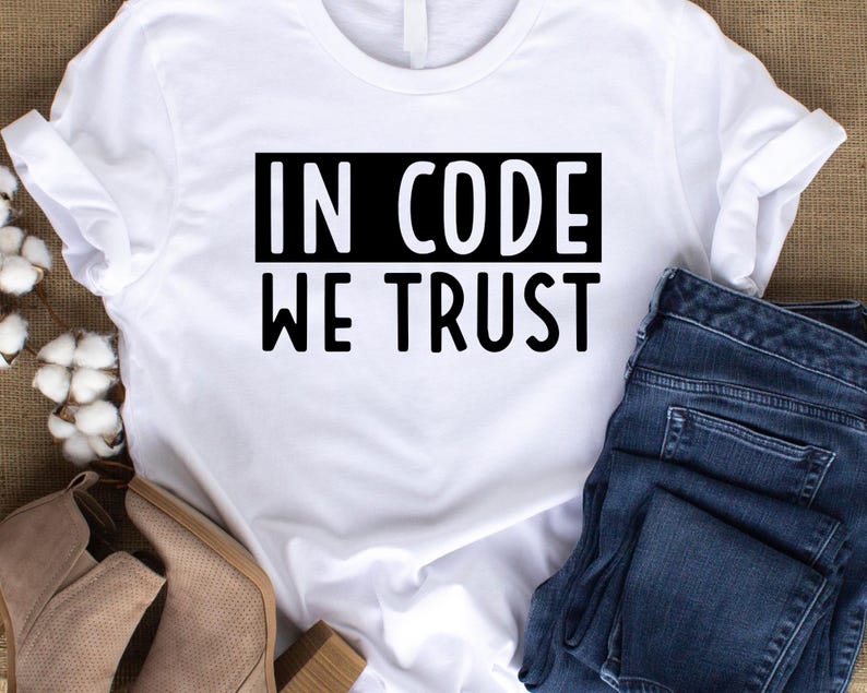 May include: White t-shirt with black text that reads "In Code We Trust".