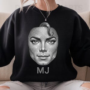 May include: Black sweatshirt featuring a detailed, sparkling portrait of Michael Jackson. The image is made of small, glittering elements, with the initials "MJ" in a similar style below the portrait. The design is centered on the front of the sweatshirt.
