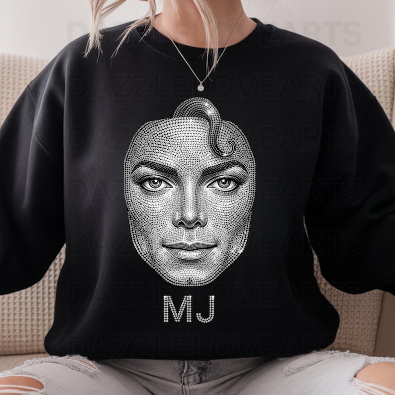 May include: Black sweatshirt featuring a detailed, sparkling portrait of Michael Jackson. The image is made of small, glittering elements, with the initials "MJ" in a similar style below the portrait. The design is centered on the front of the sweatshirt.