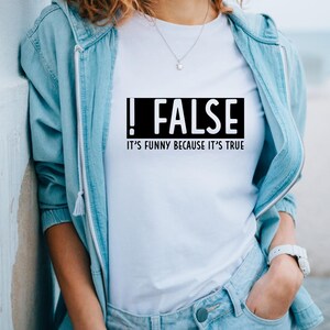 May include: White t-shirt with a black box that says "!FALSE" and "IT'S FUNNY BECAUSE IT'S TRUE" underneath.