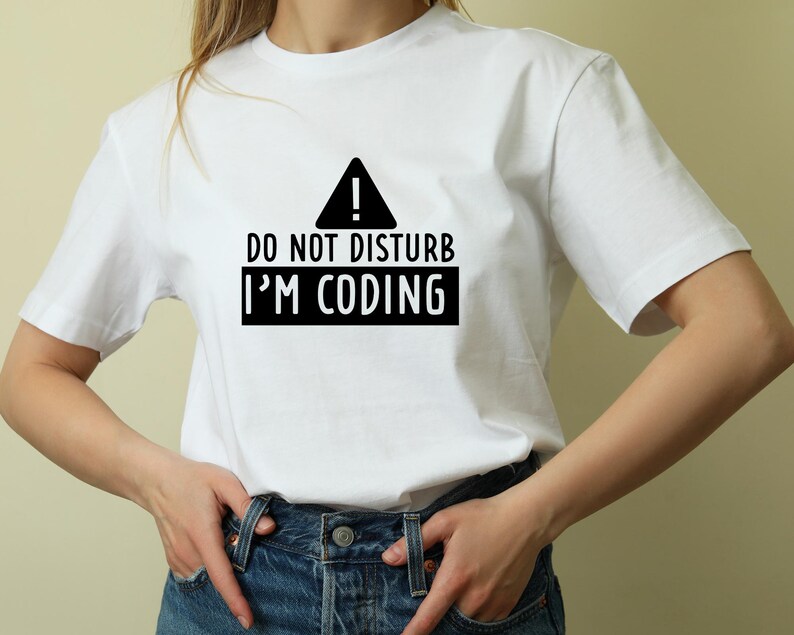May include: White t-shirt with black text that reads "Do Not Disturb I'm Coding" and a black warning sign with an exclamation point.
