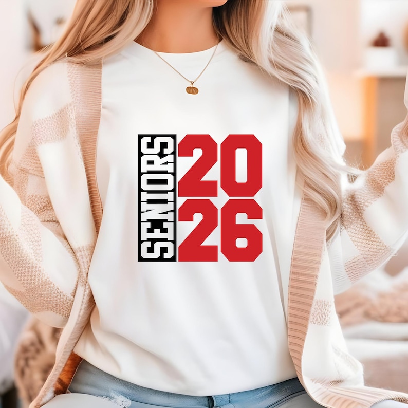 May include: White sweatshirt with the word "SENIORS" in black vertical text and the numbers "20 26" in red. The sweatshirt is a crew neck style.