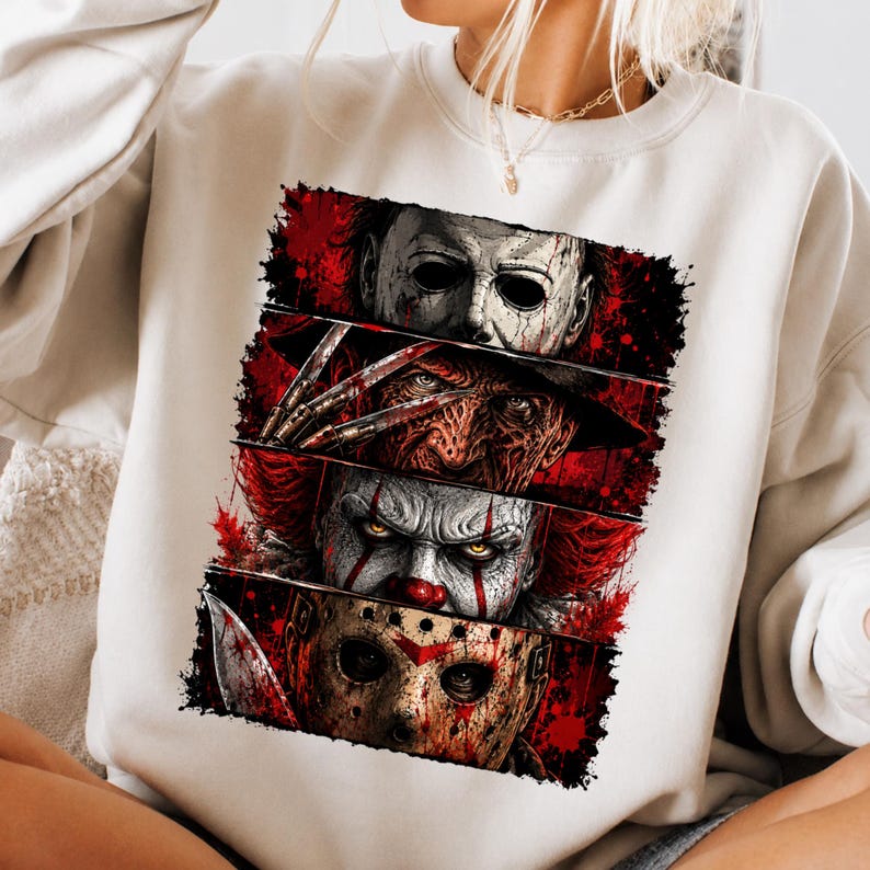 May include: A cream-coloured crewneck sweatshirt featuring a rectangular graphic print divided into four horizontal panels. Each panel displays a detailed illustration of a horror movie character, including a masked figure, a clawed hand, a clown, and a hockey mask.