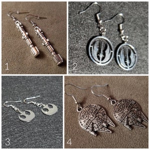 May include: Four pairs of silver Star Wars themed earrings. The first pair features a lightsaber design, the second pair features the Rebel Alliance symbol, the third pair features the Death Star, and the fourth pair features the Imperial symbol.