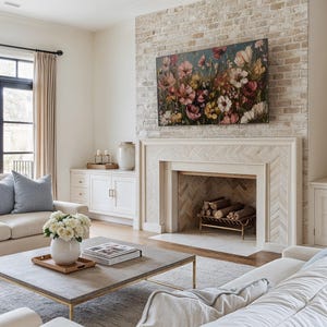 May include: A living room featuring a white sofa, a coffee table, and a fireplace with a brick surround. The fireplace has a herringbone pattern and a painting of flowers above it.