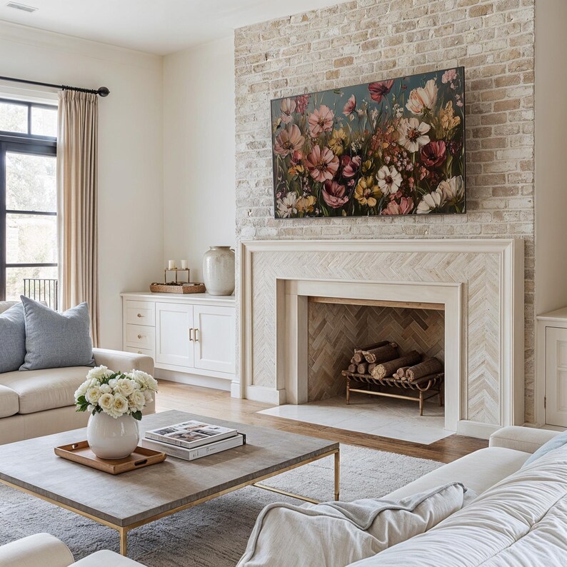May include: A living room featuring a white sofa, a coffee table, and a fireplace with a brick surround. The fireplace has a herringbone pattern and a painting of flowers above it.