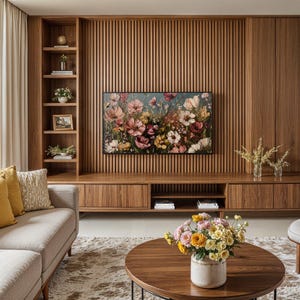 May include: A living room with a wooden wall unit featuring a TV and shelves. The wall unit is made of light brown wood with vertical slats. A beige sofa with yellow and beige throw pillows sits in front of the wall unit. A coffee table with a vase of yellow and white flowers sits in front of the sofa. A rug with a brown and beige pattern covers the floor.