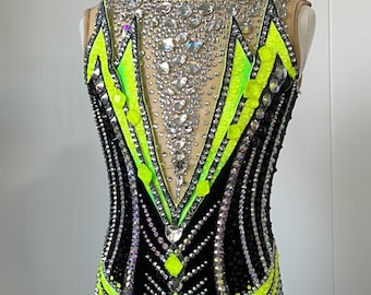 May include: Black leotard with a geometric design featuring neon green accents and rhinestones.
