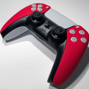 May include: A red and white PlayStation 5 DualSense controller with black buttons and a white PlayStation logo. The controller has a red and white color scheme.
