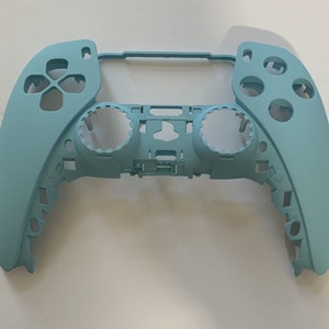 May include: A light blue video game controller shell. The controller has a directional pad, buttons, and analog stick openings. The shell is made of plastic and has a smooth finish. The controller is designed for a gaming console.