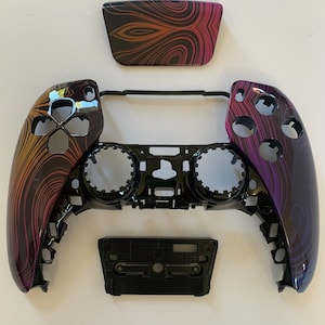 May include: A black and purple video game controller with a swirl pattern. The controller is disassembled into five pieces, including the faceplate, backplate, and buttons.