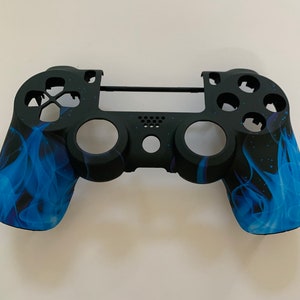 May include: Black and blue PlayStation 4 controller with a flame design.