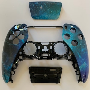 May include: A black and blue galaxy-themed controller shell for a gaming console. The shell is made of two separate pieces, one for the front and one for the back. The shell is designed to fit over the existing controller, giving it a new look.