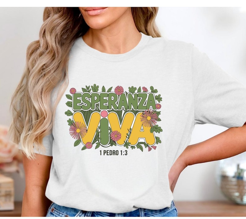 May include: White t-shirt with a green, yellow, and pink floral design. The text "Esperanza Viva" is in yellow with a green outline. The text "1 Pedro 1:3" is below the design.