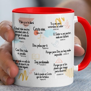 May include: White ceramic mug with a red rim and handle. The mug features inspirational quotes and bible verses in Spanish. The quotes include "Pide y se te dará", "Cristo vive", "Dios pelea por ti", "Soy perdonado", "Todo lo puedo en Cristo", "Yo y mi casa serviremos al Señor", "El Señor es mi pastor, nada me faltará", "Porque para Dios no hay nada imposible", and "Porque yo sé los planes que tengo para vosotros".