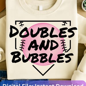 May include: A cream-coloured sweatshirt with a black baseball diamond graphic. The graphic features a pink bubble with the text "DOUBLES AND BUBBLES" in black.